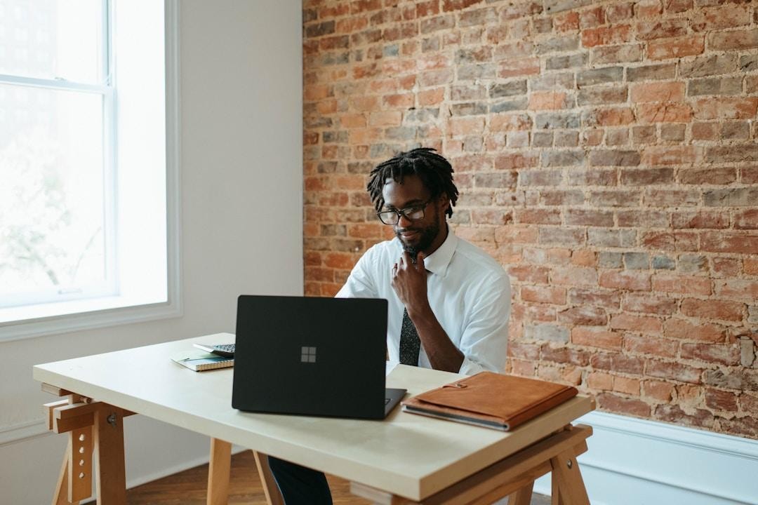 A man wearing a white shirt and tie is seated at a desk, using a laptop that showcases AI integration technology